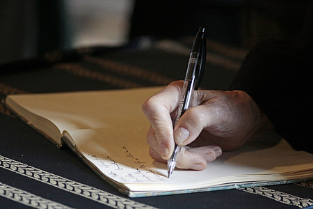 person holding ballpoint pen writing on white paper thumbnail