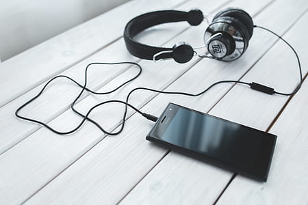 Black smartphone and headphones on a desk thumbnail