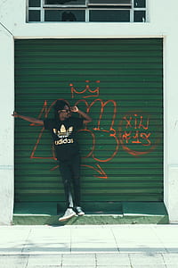 man in black adidas shirt standing against roller shutter thumbnail