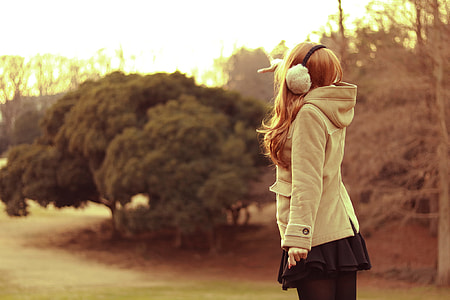 woman in hooded coat standing on green grass field thumbnail