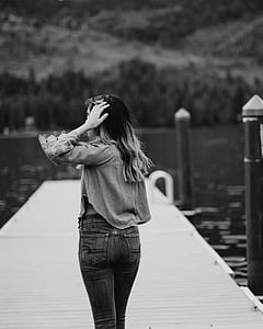grayscale photography of woman standing on boardwalk thumbnail