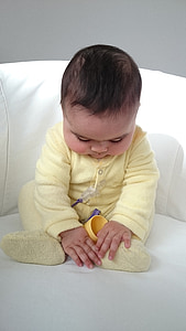 baby sitting on white sofa chair thumbnail