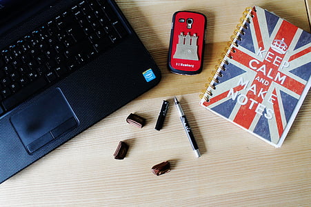 laptop on table beside phone, pen, and notebook thumbnail