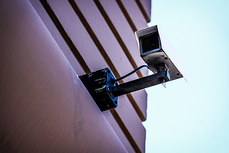 worm's eye view photography of white CCTV camera mounted on brown building during daytime thumbnail