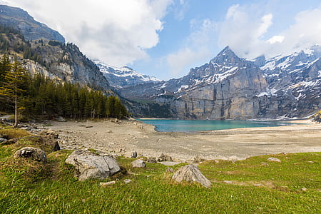 body of water near cliff and trees during daytime thumbnail