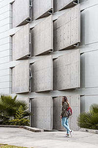 woman waking beside beside building while smiling during daytime thumbnail