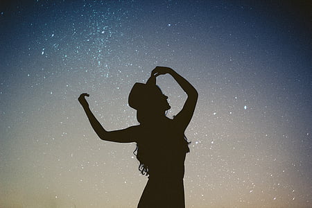 silhouette of woman wearing hat under starry night thumbnail
