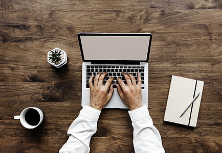 person using MacBook Pro on brown wooden table thumbnail