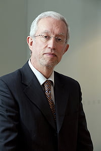 man wearing black suit jacket near wall thumbnail