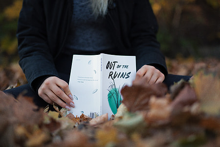 person reading Out of the Ruins book on field during daytime thumbnail