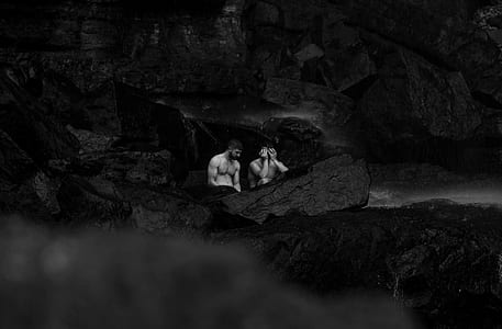 two nude man standing on stone hill grayscale photo thumbnail