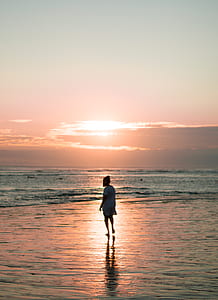 woman walks on seashore during golden hour thumbnail