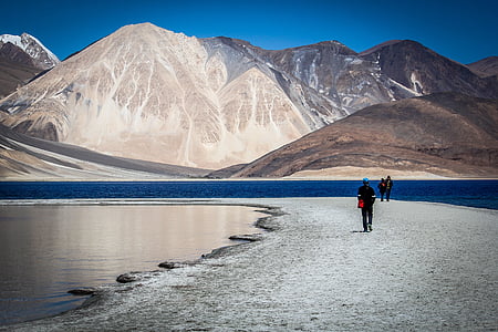 photo of person walking on pathway near mountain thumbnail
