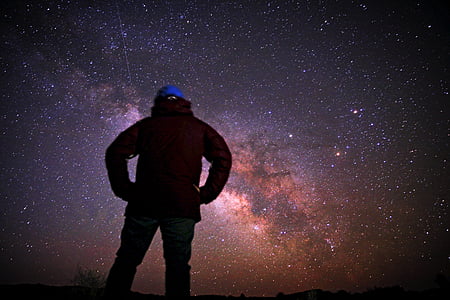 person standing overlooking stars at night time thumbnail