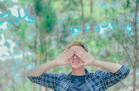 Man Covered Eyes by His Hand Standing on Surrounded Trees thumbnail