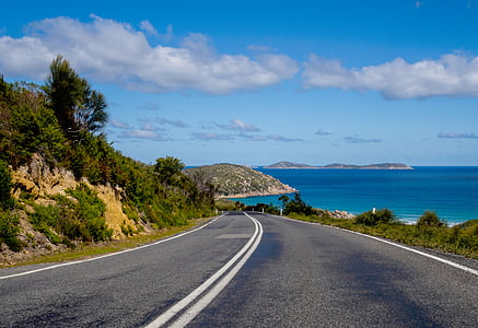 gray concrete road beside body of water thumbnail