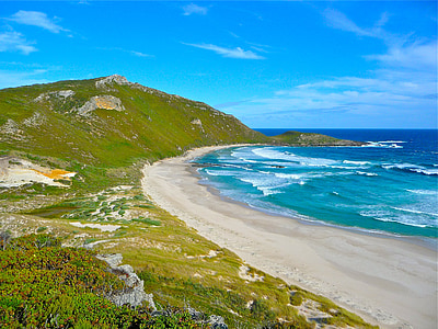 seashore near green mountain during daytime thumbnail