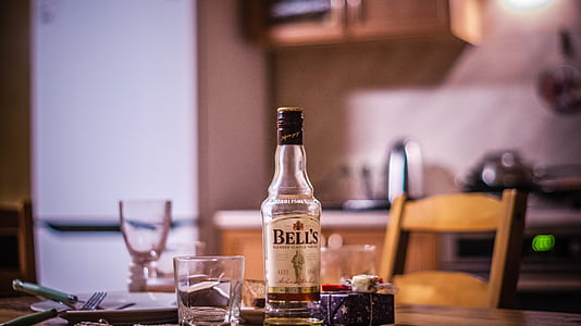 clear Bells whiskey bottle on brown wooden table thumbnail