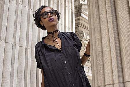 woman wearing gray shirt while holding to white pillar thumbnail