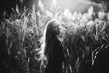 grayscale photo of woman standing near grass thumbnail