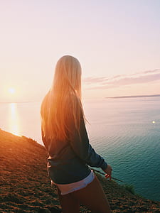 woman standing on hill near body of water thumbnail