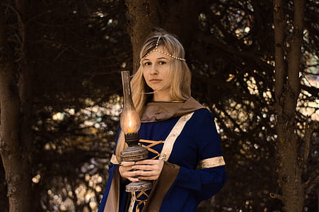 woman wearing blue and brown dress holding kerosene lamp thumbnail