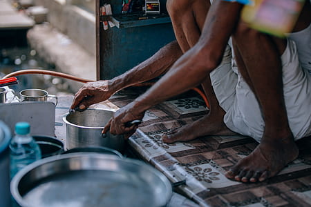 person squatting while holding cooking pot thumbnail