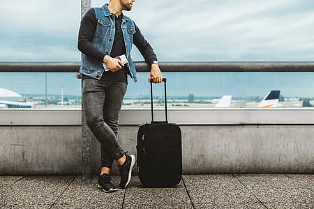 Calm male tourist is standing outdoor in airport and looking at airplanes. thumbnail