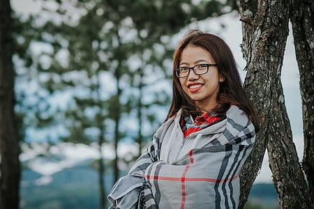 smiling woman leaning on tree during daytime thumbnail
