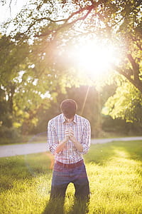man in white and purple plaid dress shirt kneeling while praying thumbnail