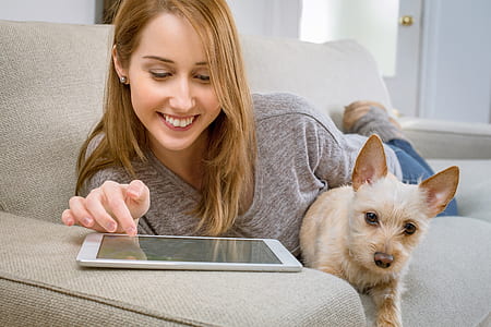 woman lying on her stomach beside puppy inside the room thumbnail