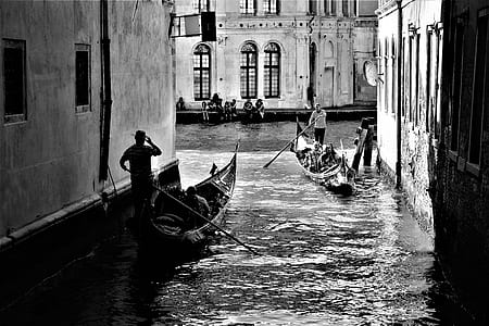 grayscale photo of person standing on canoe boats thumbnail