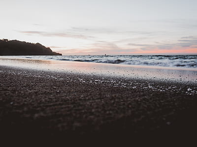 seashore near mountain during day time thumbnail