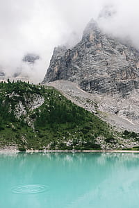 river beside clouds covered mountain during day time thumbnail