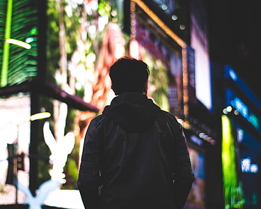 selective focus photography of person in leather jacket during nightime with LED signages background thumbnail