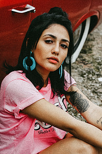 woman wearing pink shirt sitting beside red vehcile thumbnail