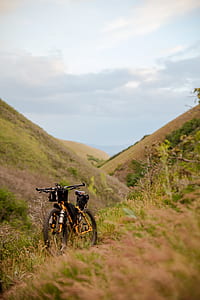 photo of yellow hardtail bike on green grass near mountain thumbnail