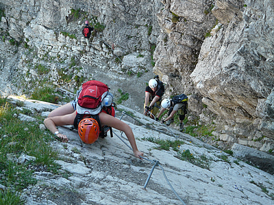three person climbing on cliff near rock during daytime thumbnail