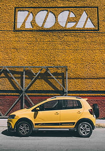 yellow 5-door hatchback parked next to wall with ROCA signage thumbnail