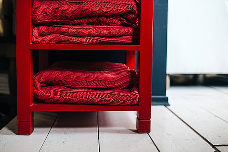 Folded sweaters and fabrics stacked on shelves thumbnail