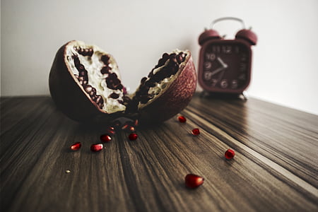pomegranate fruit on wooden table near bell alarm clock thumbnail