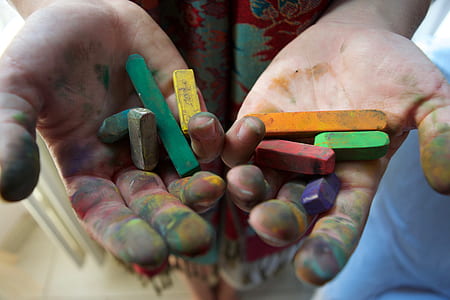 selective focus photography of person's painted palm with crayons on top thumbnail