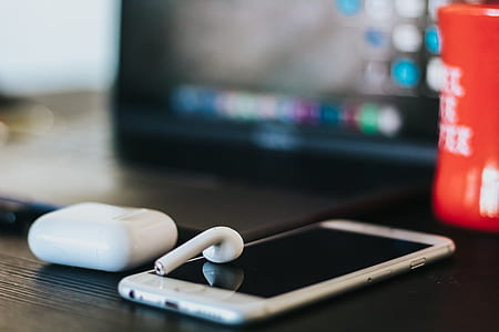 person showing silver iPhone with AirPods thumbnail