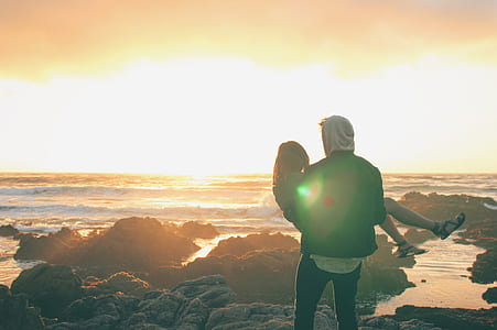 man carrying woman on rocky shore thumbnail