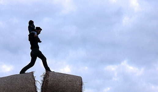 man carrying child under cloudy sky during daytime thumbnail