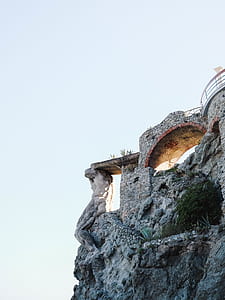 brown concrete stone bridge near cliff during daytime thumbnail