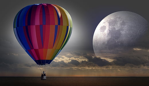 red, blue, and yellow hot air balloon flying under grey cloudy sky thumbnail