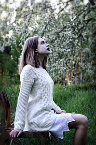 woman sitting on brown wooden chair on green grass during daytime thumbnail