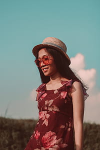 woman in red and pink floral sleeveless top wearing brown wicker hat thumbnail