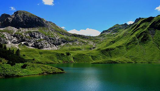 landscape photography of green mountains near body of water during day time thumbnail